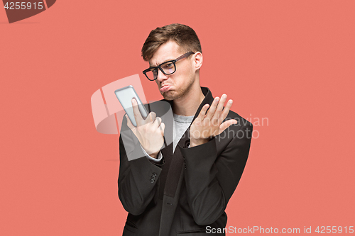 Image of The young caucasian businessman on red background talking on cell phone