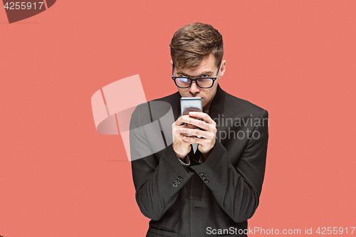 Image of The young caucasian businessman on red background talking on cell phone