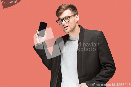 Image of The young caucasian businessman on red background talking on cell phone