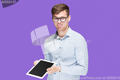 Image of The young man in a shirt working on laptop on lilac backgroundin