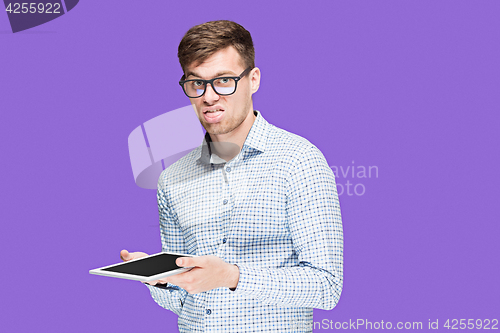 Image of The young man in a shirt working on laptop on lilac backgroundin