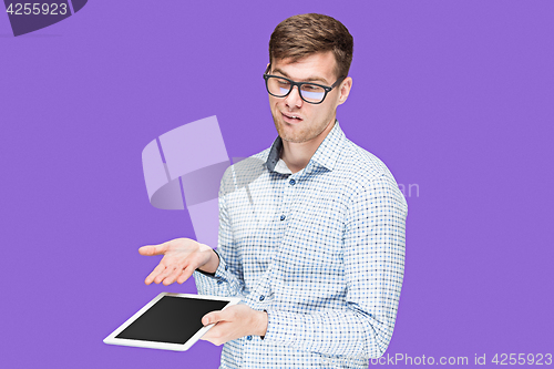 Image of The young man in a shirt working on laptop on lilac backgroundin