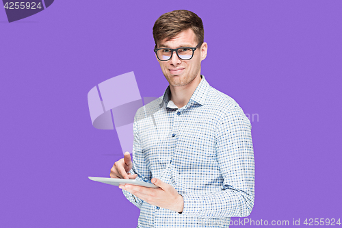 Image of The young man in a shirt working on laptop on lilac backgroundin