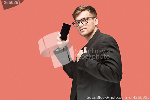 Image of The young caucasian businessman on red background talking on cell phone