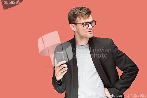 Image of The young caucasian businessman on red background talking on cell phone