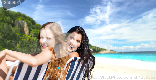 Image of happy women sunbathing on chairs over summer beach