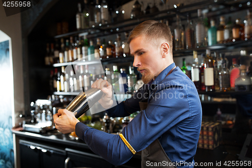 Image of barman with shaker preparing cocktail at bar