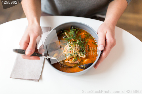 Image of woman eating seafood soup at restaurant