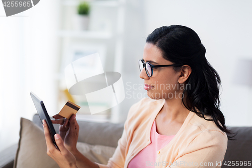 Image of happy woman with tablet pc and credit card at home