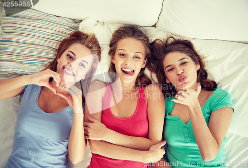 Image of happy young women in bed at home pajama party