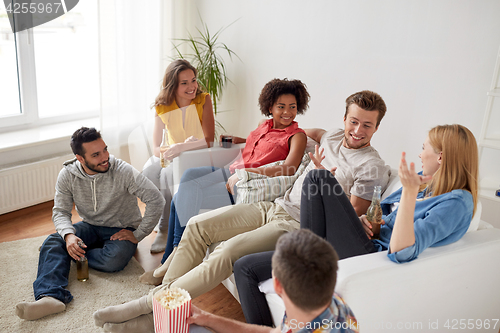 Image of happy friends with popcorn and beer at home