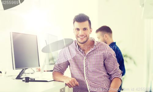 Image of happy creative man with computer at office