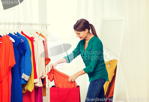 Image of happy woman with shopping bags and clothes at home