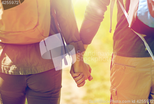 Image of close up of couple with backpacks holding hands