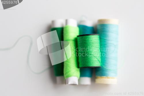 Image of green and blue thread spools on table