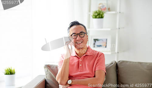 Image of happy man calling on smartphone at home