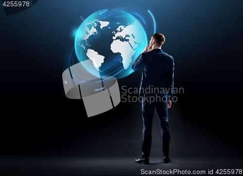Image of businessman looking at earth globe hologram