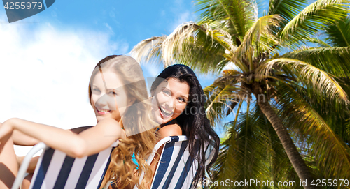 Image of happy women sunbathing on chairs over summer beach