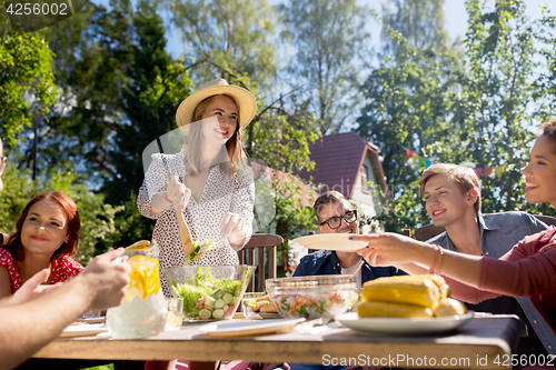 Image of happy friends having dinner at summer garden party