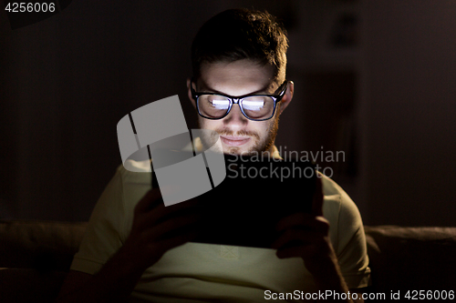 Image of young man with tablet pc networking at night