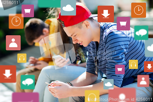 Image of happy teenage friends with smartphones outdoors