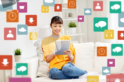 Image of happy young asian woman with tablet pc at home