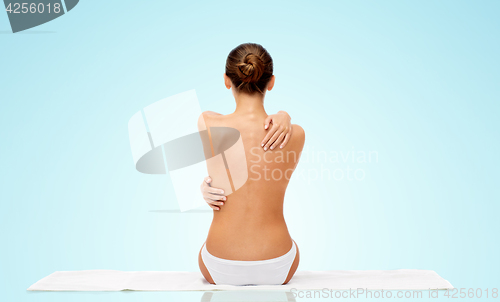 Image of beautiful topless young woman on towel from back