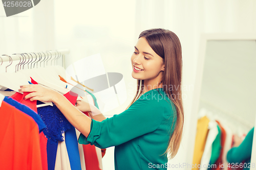 Image of happy woman choosing clothes at home wardrobe