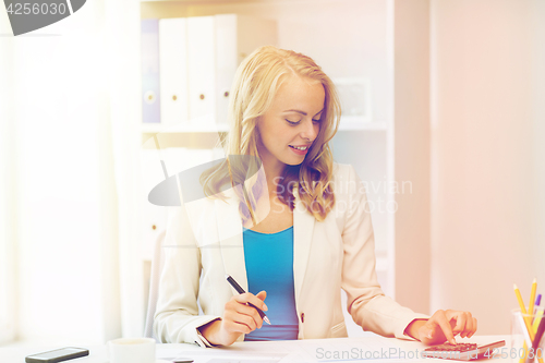 Image of businesswoman with calculator counting at office