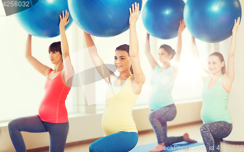 Image of happy pregnant women exercising with ball in gym