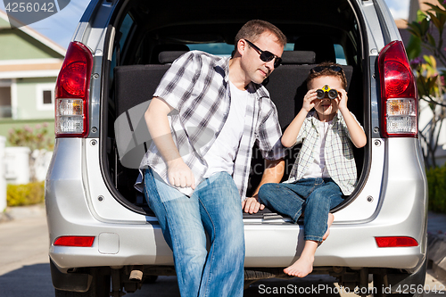 Image of Happy father and son getting ready for road trip on a sunny day.