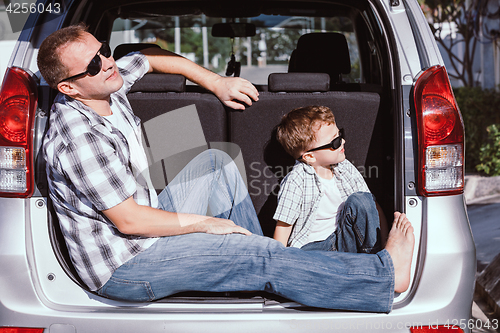 Image of Happy father and son getting ready for road trip on a sunny day