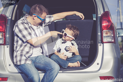 Image of Happy father and son getting ready for road trip on a sunny day