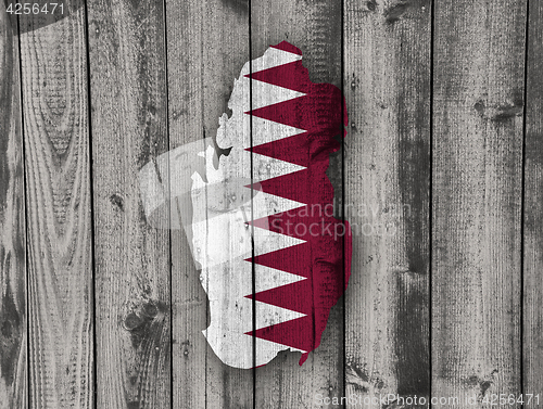 Image of Map and flag of Qatar on weathered wood
