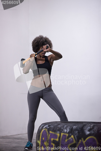 Image of black woman workout with hammer and tractor tire