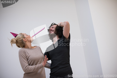 Image of couple in party hats blowing in whistle