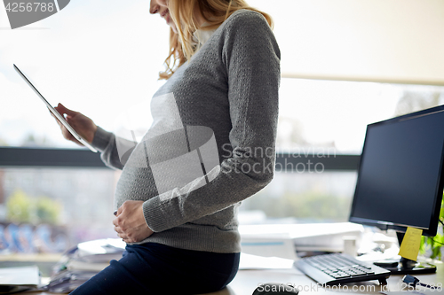 Image of pregnant businesswoman with tablet pc at office