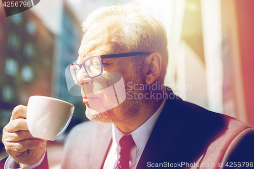 Image of senior businessman drinking coffee on city street