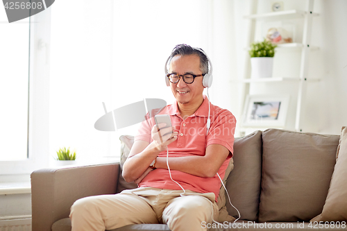 Image of man with smartphone and headphones at home