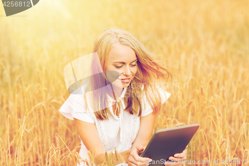 Image of happy young woman with tablet pc on cereal field