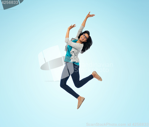 Image of smiling young indian woman jumping in air