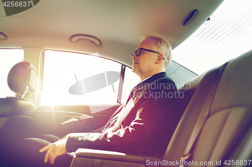 Image of senior businessman driving on car back seat