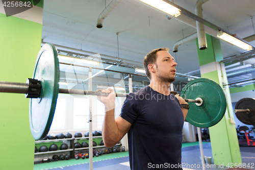 Image of man doing exercise with barbell in gym