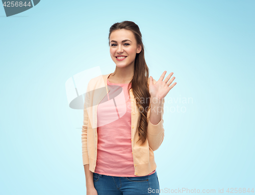 Image of happy smiling young woman waving hand over white