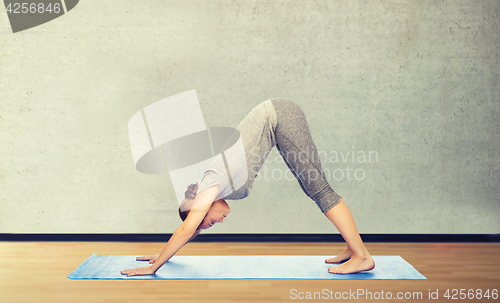 Image of woman making yoga dog pose on mat