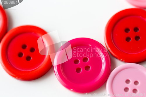 Image of red and pink sewing buttons on white background