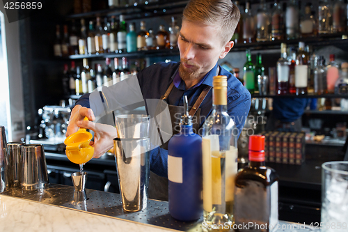 Image of barman with shaker, alcohol and jigger at bar