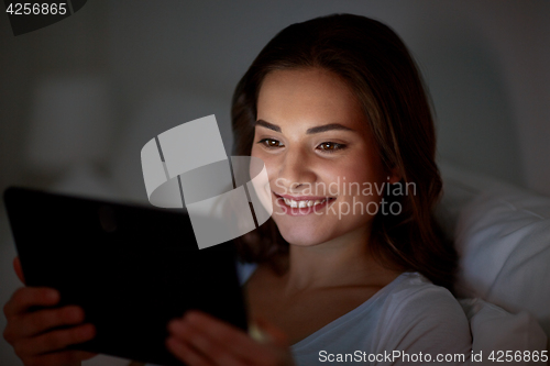 Image of young woman with tablet pc in bed at home bedroom