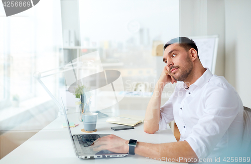 Image of businessman with laptop thinking at office