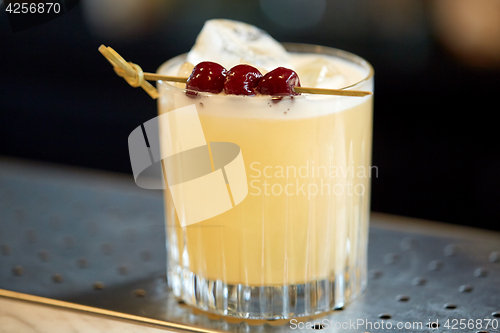 Image of glass of cocktail with cherries at bar